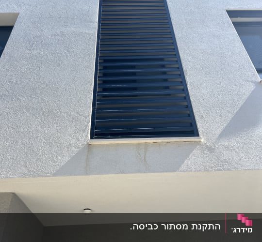 תריסי אלומיניום שחורים על קיר חיצוני לבן
